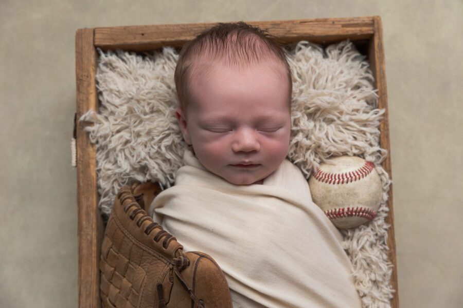Studio photo of newborn sleeping peacefully in a cream blanket